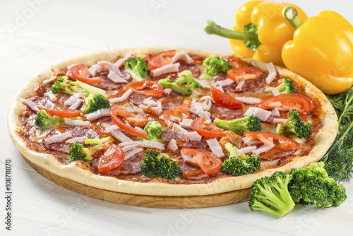 tasty pizza on a wooden board with pepper and broccoli