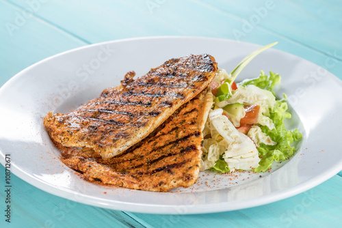 chicken grilled with fresh salad mix on the painted wooden backg