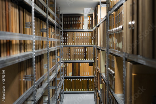 Indoor storage room details in a manufacturing enterprise, metal shelves with wooden brown office cases with folders. photo