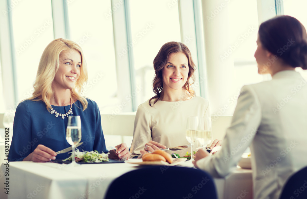 happy women eating and talking at restaurant happy women eating and talking at restaurant