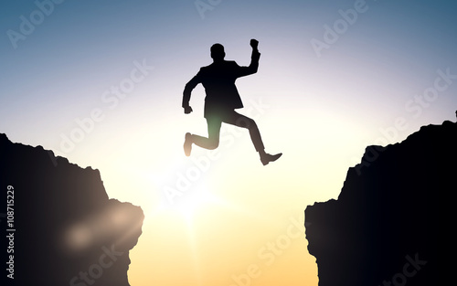 happy businessman jumping between rocks