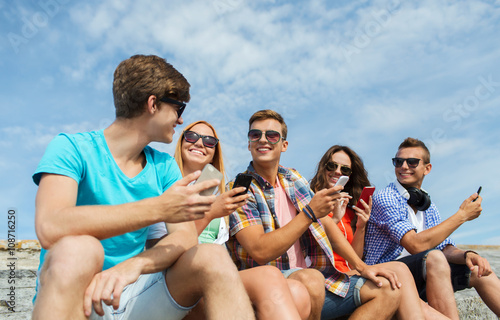 group of happy friends with smartphones outdoors