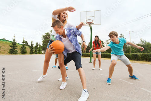 group of happy teenagers playing basketball
