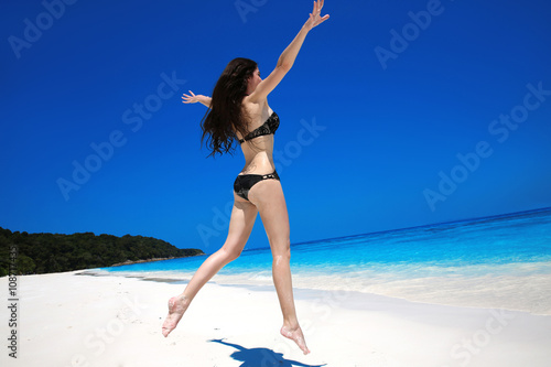 Brunette Woman jumping On Tropical Beach. Summer vacation. Happy