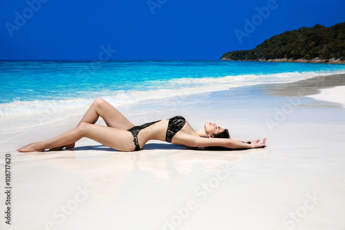 Beautiful sexy bikini model woman lying on exotic tropical beach