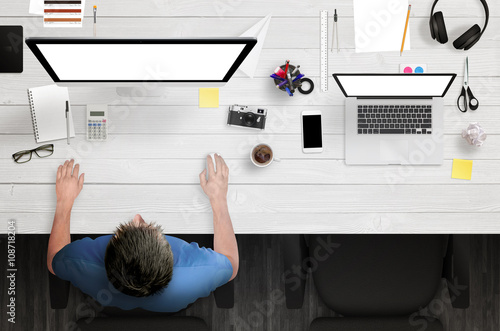 Man work on computer with white isolated screen. Work desk with laptop, paper, camera, coffee, notepad, pens, glasses, calculator, scissors. Top view.