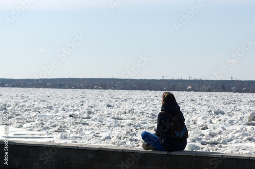 A young woman watches the ice on the river