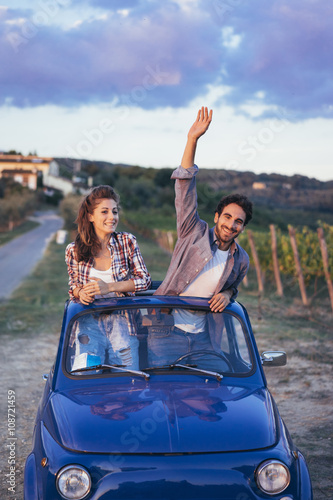 Young couple doing a road trip in Tuscany countryside in a vintage car © juripozzi