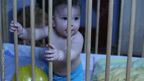 Smiling baby playing in a baby bed
 photo