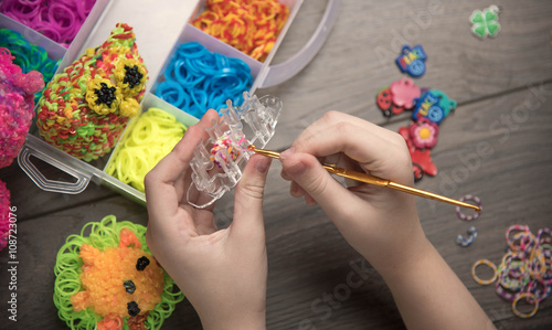 children's hands are weaving figures out colored rubbers