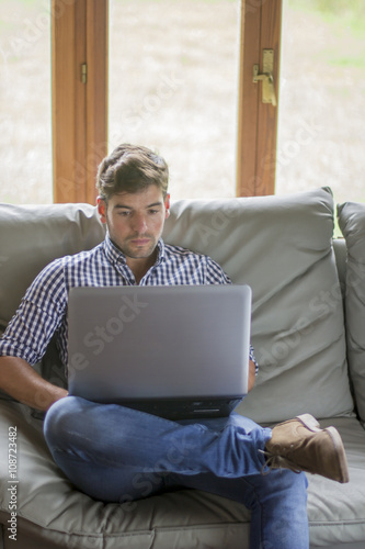 Frontal view of focused young man wearing plaid shirt sitting on