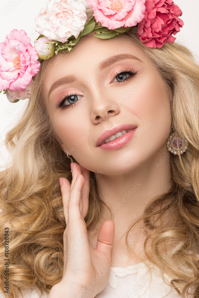 Close-up beauty portrait. Beautiful blonde girl with wreath of flowers. Touching face. Looking at camera. Isolated on white background