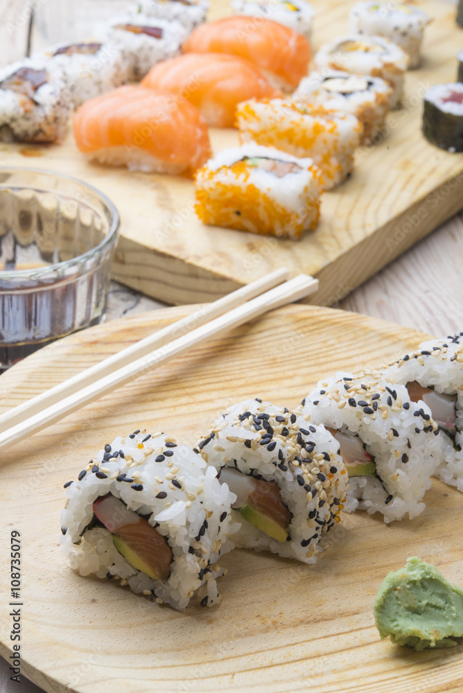 Different Sushi rolls,wasabi and ginger on a plate on wooden bac Different Sushi rolls,wasabi and ginger on a plate on wooden bac