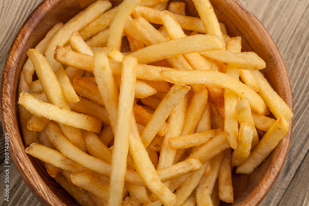 French fries in a wooden bowl, on a wooden background. French fries in a wooden bowl, on a wooden background.
