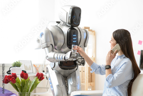 Pleasant robot giving glass of water to girl 