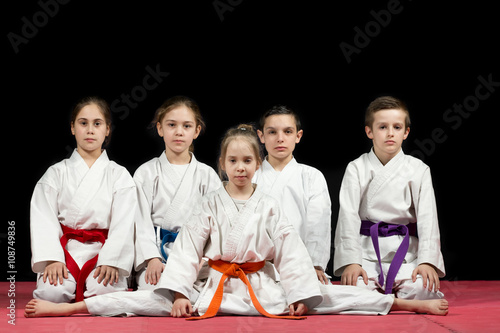 Children in kimono sitting on tatami on martial arts seminar. Selective focus