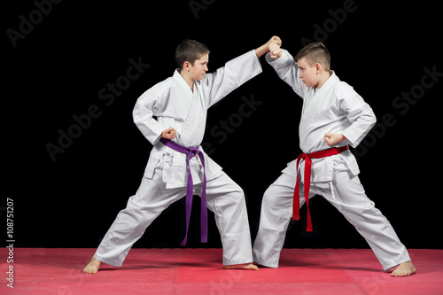 Two boys in white kimono fighting isolated on black background