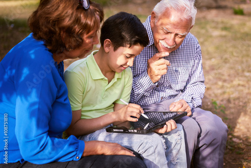 Grandparents And Grandson Studying Homework On Tablet PC