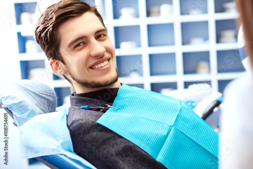 Portrait of male. smile face. Dental care Concept. Dental inspection is being given to Beautiful man surrounded by dentist and his assistant photo