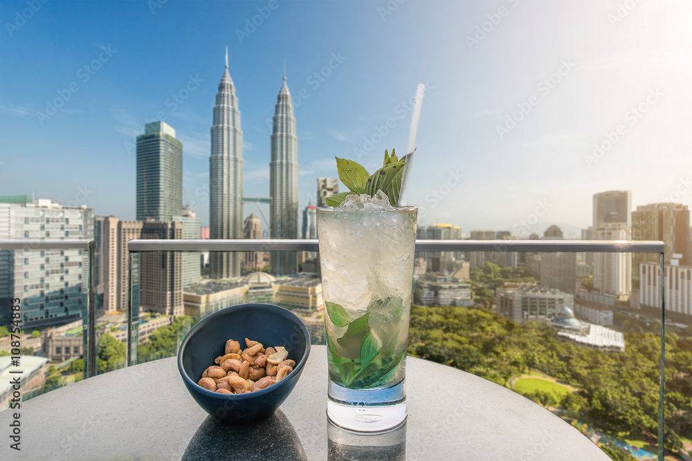 Obraz premium Mojito cocktail and cashews on table in rooftop bar at Kuala Lum