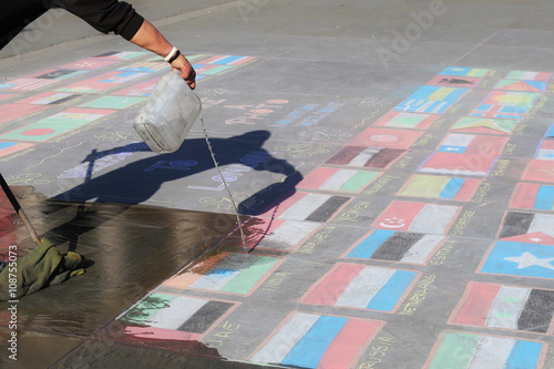 London, UNITED KINGDOM, 09.04.2016. A man cleaning states flags made of chalk, symbolizing nation states crisis