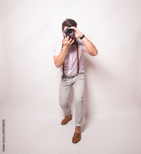 Young bearded treveler man with photocamera on white background