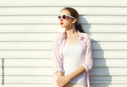 Fashion pretty young woman in sunglasses over white background