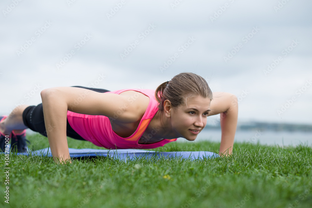 Young woman doing push up exercises at quay Young woman doing push up exercises at quay