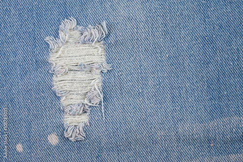 Blue jeans background closeup view to torn texture.