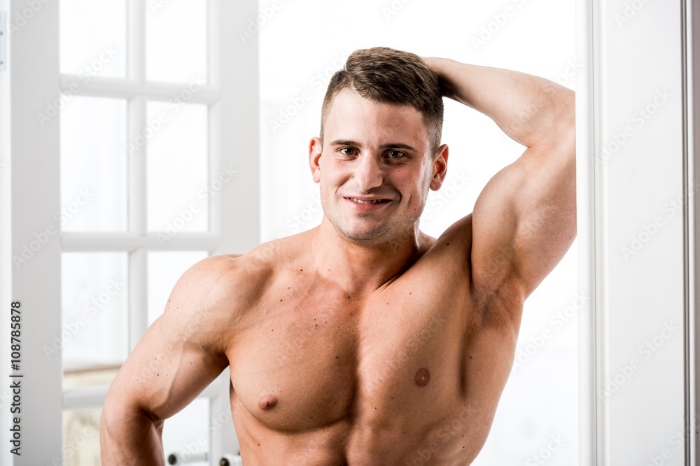 Obraz premium Portrait of a well built shirtless muscular male model against light background