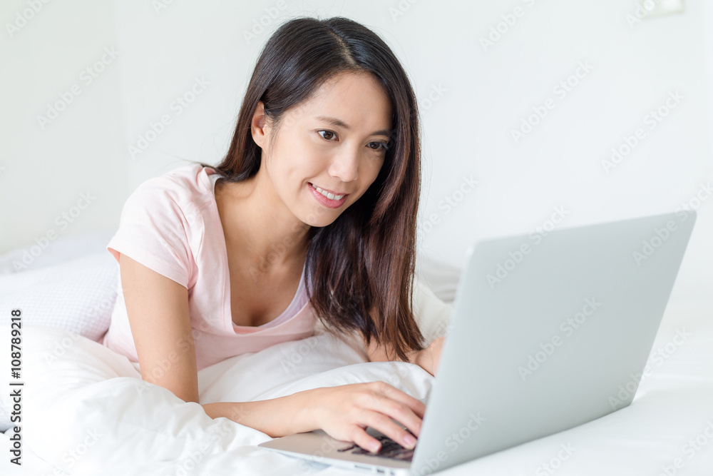 Woman lying down the bed in front of her laptop Woman lying down the bed in front of her laptop