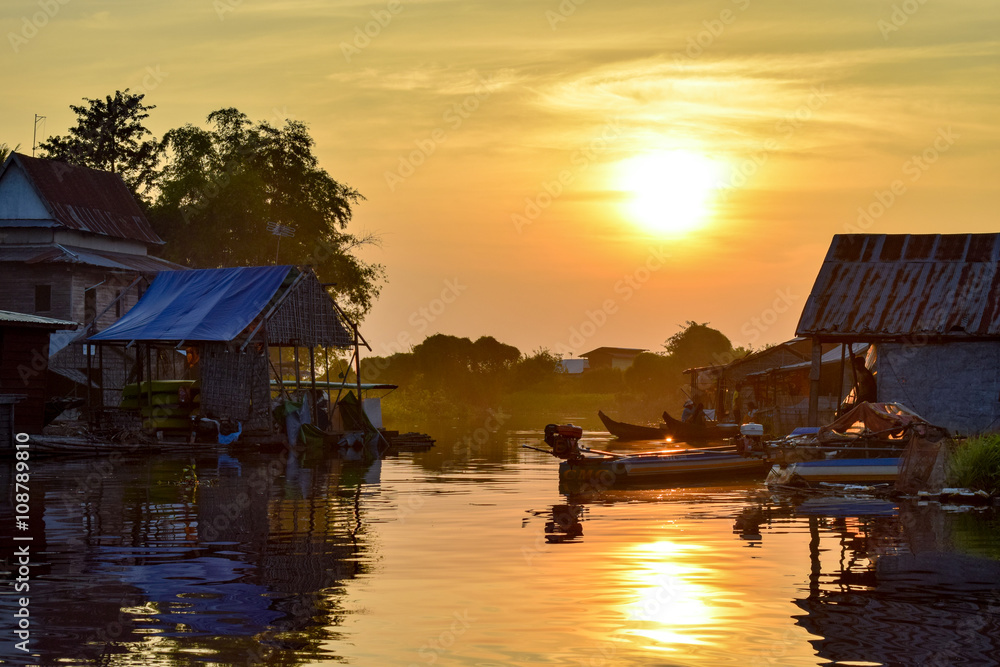 Fototapeta premium Boats and floating village houses on a river at sunset