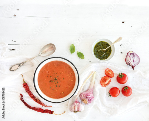 Fototapeta Naklejka Na Ścianę i Meble -  Gazpacho soup in rustic metal bowl with fresh tomatoes, green sauce, chili, garlic and basil