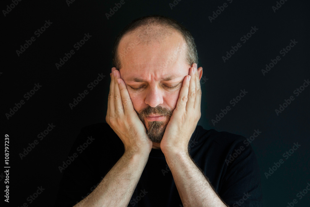 Portrait of an adult man with beard and mustaches on black background, eyes closed, having headache Portrait of an adult man with beard and mustaches on black background, eyes closed, having headache