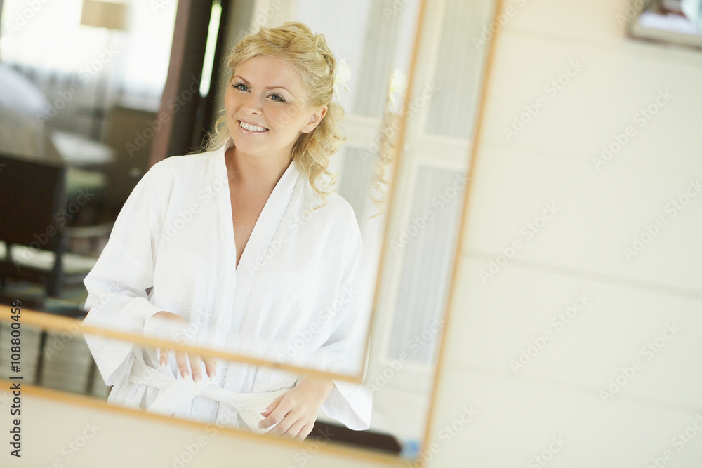 Gorgerous bride standing in front of mirror and fixing her hair Gorgerous bride standing in front of mirror and fixing her hair