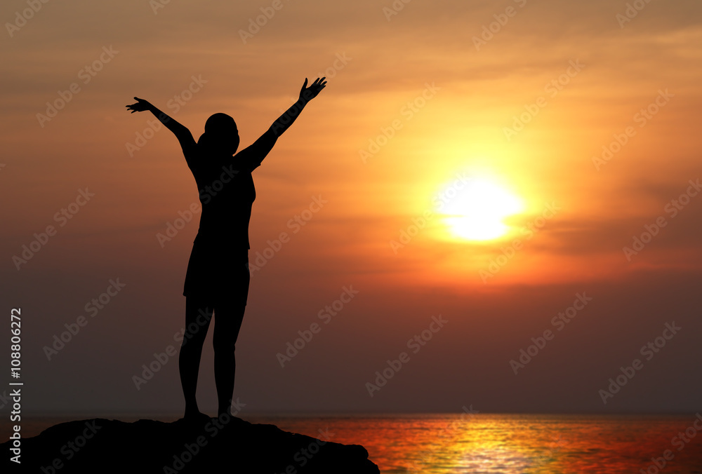 silhouette of woman with raised hands on the beach