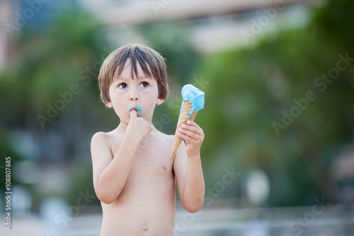 Sweet little child, boy, eating ice cream on the beach