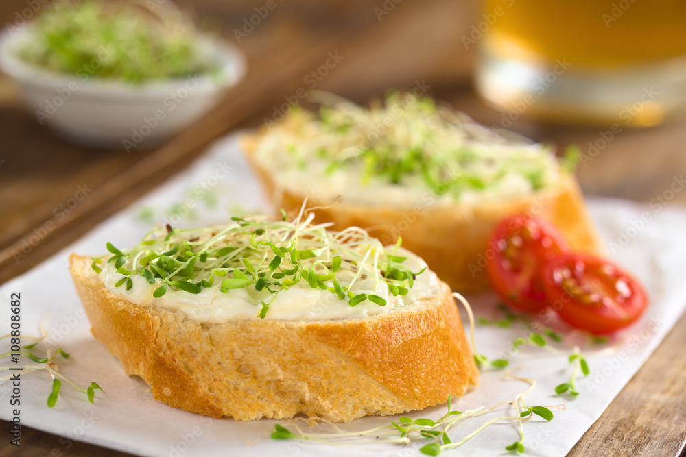 Baguette slices spread with cream cheese and sprinkled with alfalfa sprouts on sandwich paper (Selective Focus, Focus on the front of the cream cheese and sprouts on the first baguette slice) Baguette slices spread with cream cheese and sprinkled with alfalfa sprouts on sandwich paper (Selective Focus, Focus on the front of the cream cheese and sprouts on the first baguette slice)