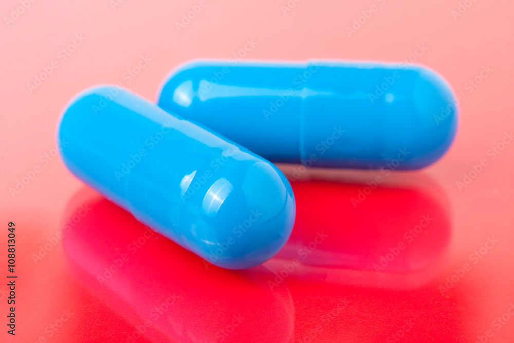 two blue pills on a red background close-up macro two blue pills on a red background close-up macro
