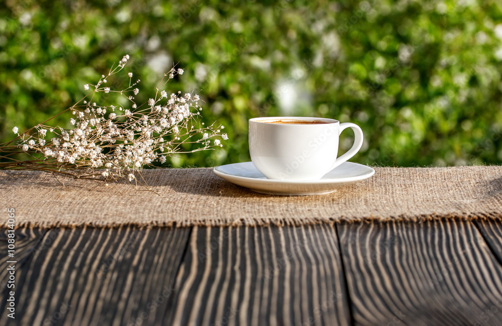 Cup of coffee on a wooden table in sunshine