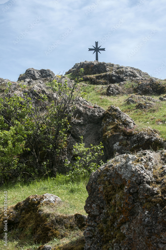 Fototapeta premium Christian cross on rocky mountain hill on blue sky background