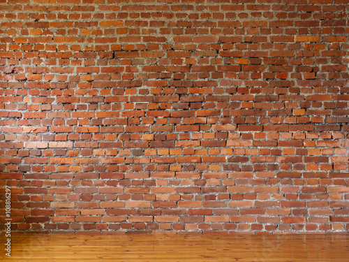 Room with red brick walls and wooden flooring of boards
