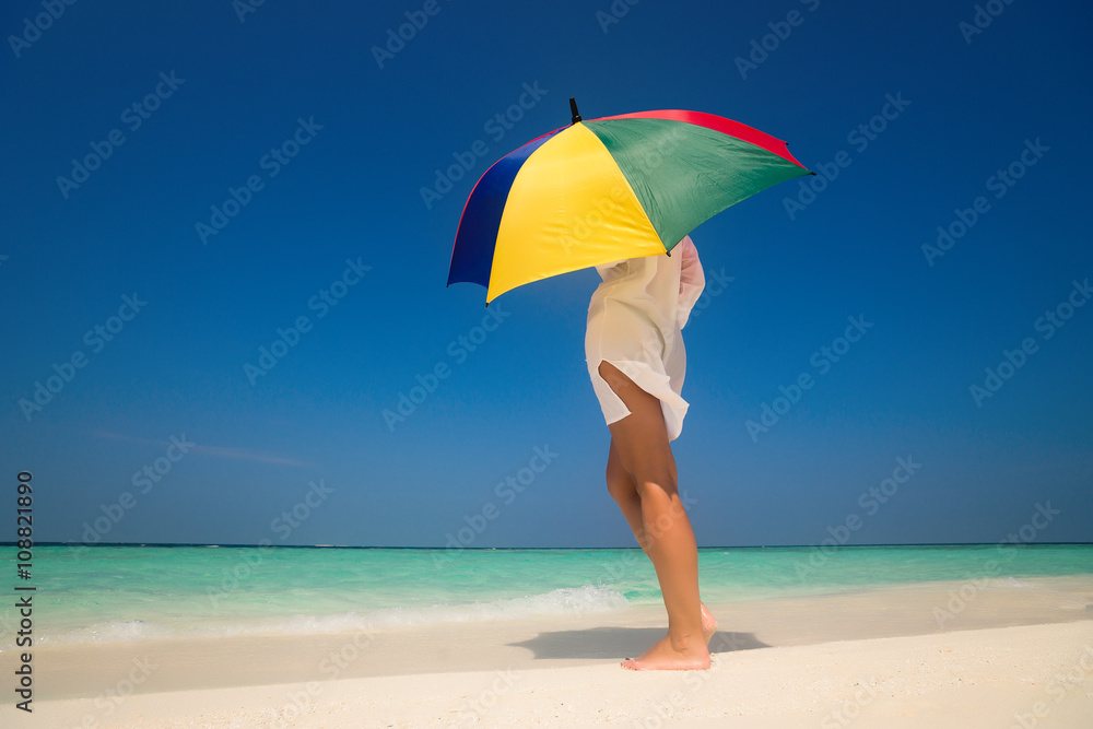 Girl with an colorful  umbrella on the sandy beach