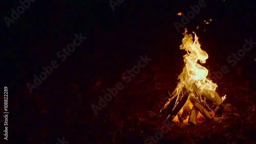 Outdoor wood campfire burring brightly at night forest with sparks