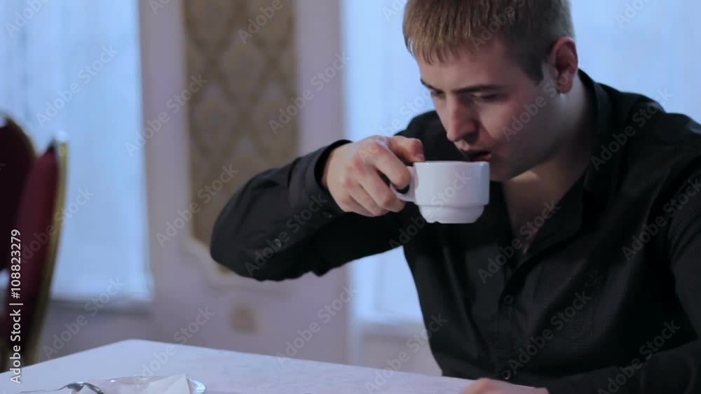 Man Using Tablet PC and Drinking Coffee in Cafe Man Using Tablet PC and Drinking Coffee in Cafe