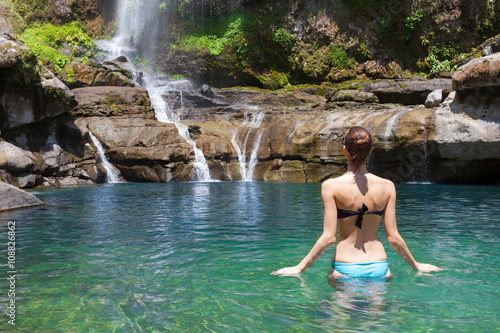 Woman going for a swim in a tropical waterfall spring setting.