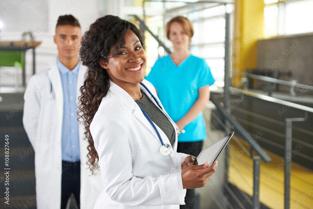 Fototapeta premium Portrait of a friendly female african american doctor and team in bright modern office