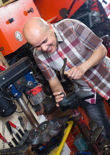 Workman repairing pair of shoes . © JackF