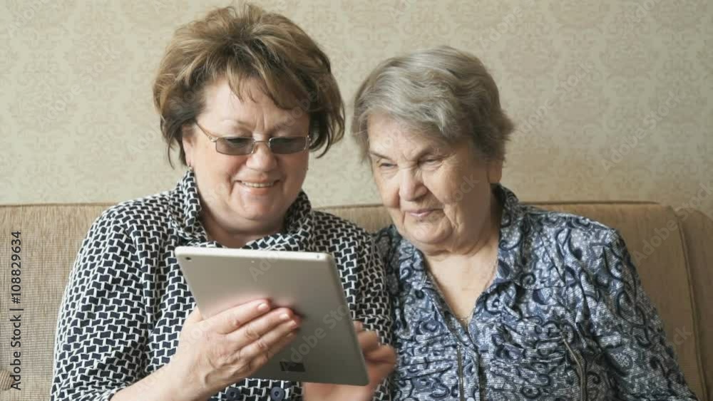 Two elderly women watch pictures using a tablet Two elderly women watch pictures using a tablet