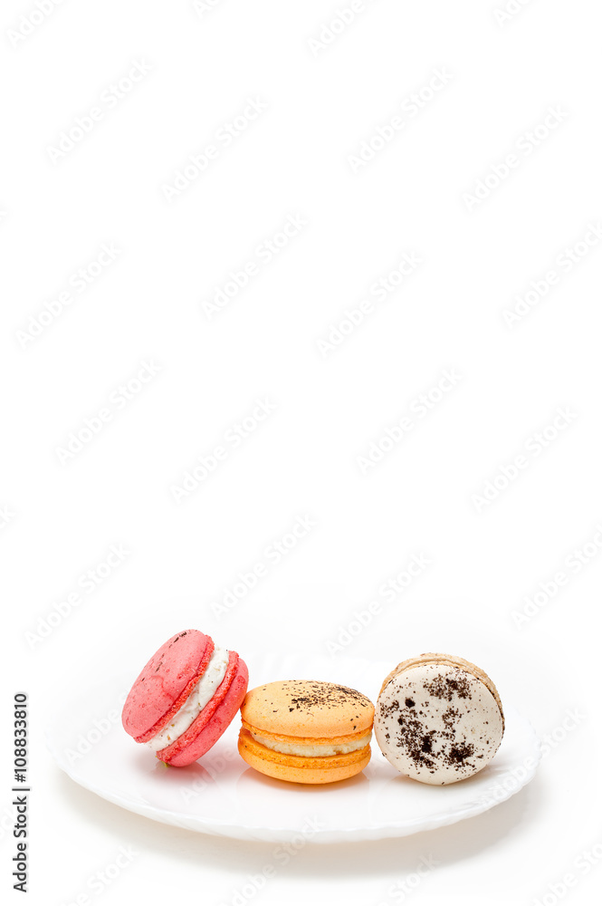 Collection of brightly colored French macarons on white plate and white background